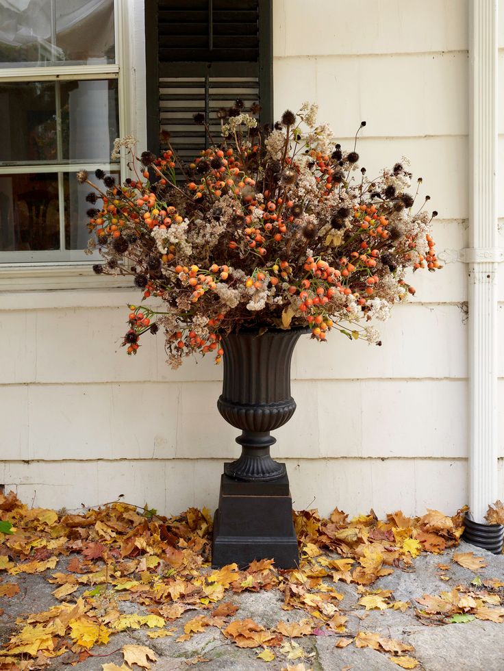 a black vase filled with lots of flowers on top of a sidewalk