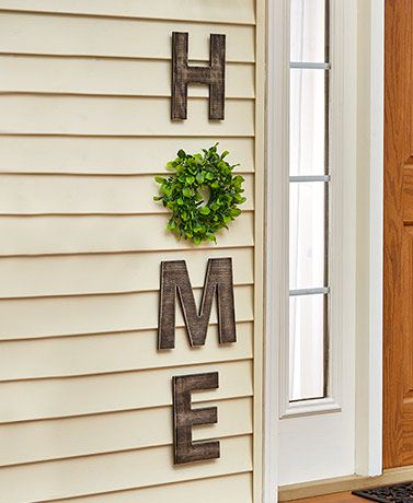 the front door is decorated with metal letters and a wreath that says home on it