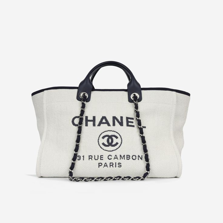 Chanel's interpretation of the perfect shopping tote. The Deauville comes in various finishes from leather, to tweeds and fabrics. It's spacious enough to hold everything you would need throughout the day, the Deauville is suitable for travelling, a day at the beach or just running errands.  SPL Exterior  White raffia / mixed fabrics  Navy calfskin/fabric trims  Silver-tone hardware   "Chanel", "Rue Cambon Paris" embroidered  Two leather top handles Two interwoven chain / fabric shoulder straps Small magnetic button closure 2018/19 production  Excellent condition - some staining to raffia / some marks to handles   Interior  Navy fabric lining  Spacious compartment One zip pocket Two slip pockets  Excellent condition - some signs of use  Sold with card    SPL  Height 44cm Width 32cm Depth 2 Chanel Rue Cambon, Chanel Tote, Black Felt, Felt Bag, A Day At The Beach, Navy Leather, Chanel Deauville Tote Bag, Mixing Fabrics, Bags And Purses