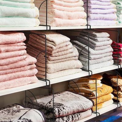 towels and blankets are stacked on shelves in a store, with one folded up next to the other