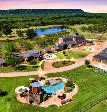 an aerial view of a home with a tennis court and pool in the foreground