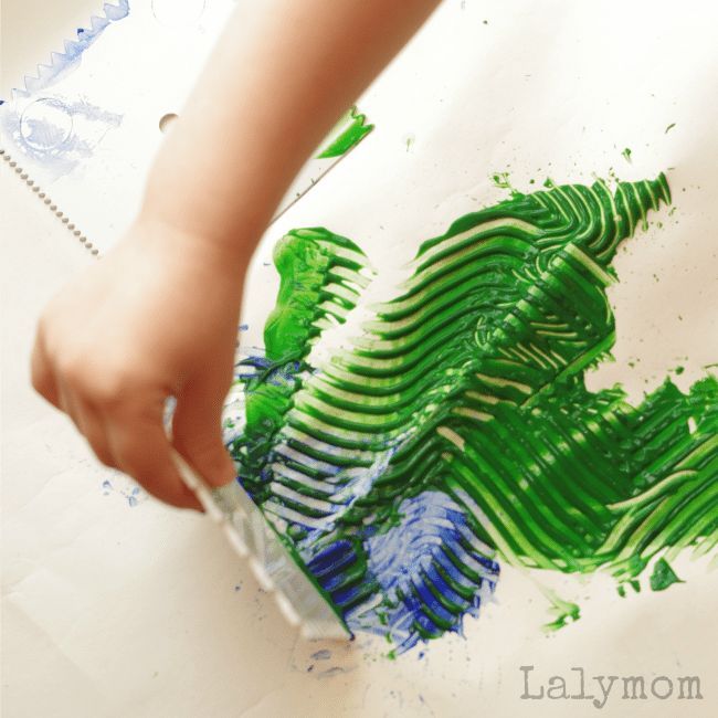 a child is painting with green and blue paint