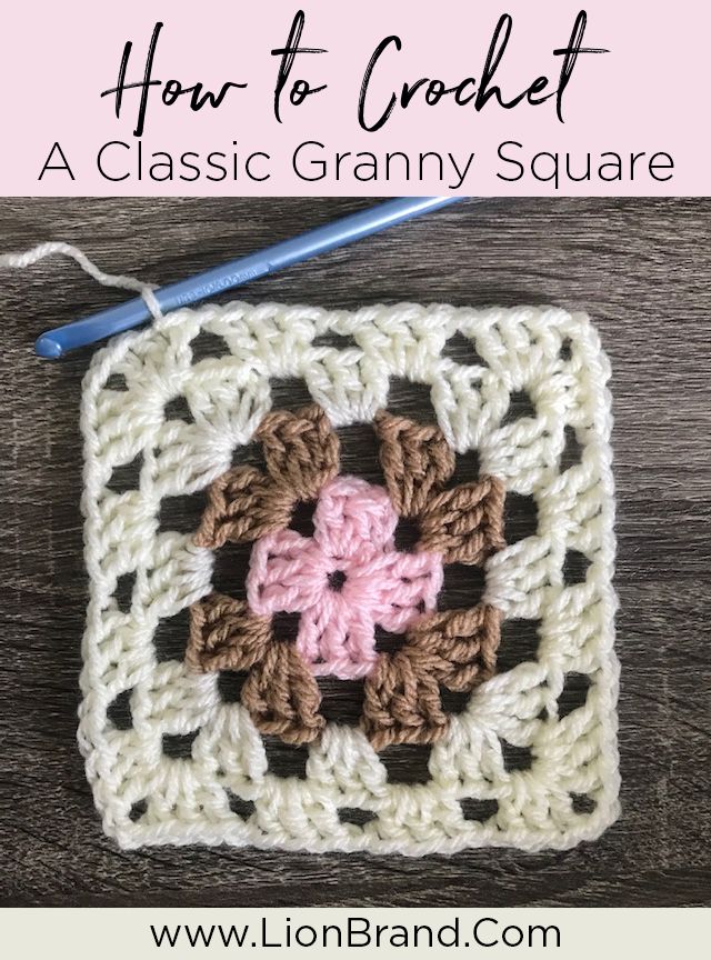 a crocheted square with a pink flower on it and a blue ball of yarn next to it