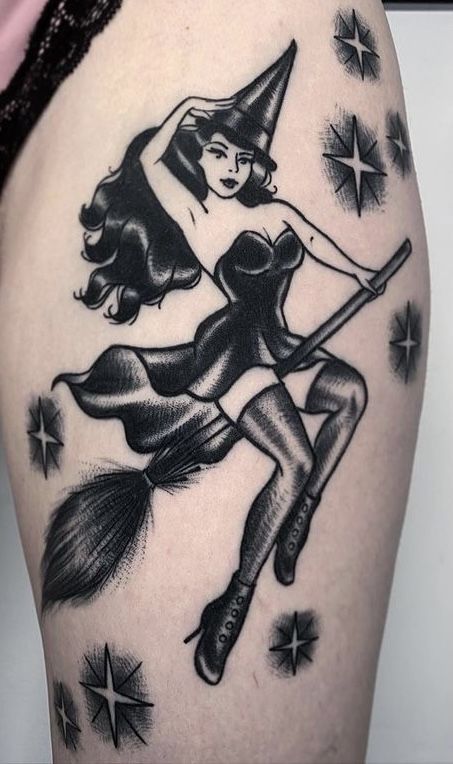 a black and white tattoo of a witch on the thigh with stars around her legs