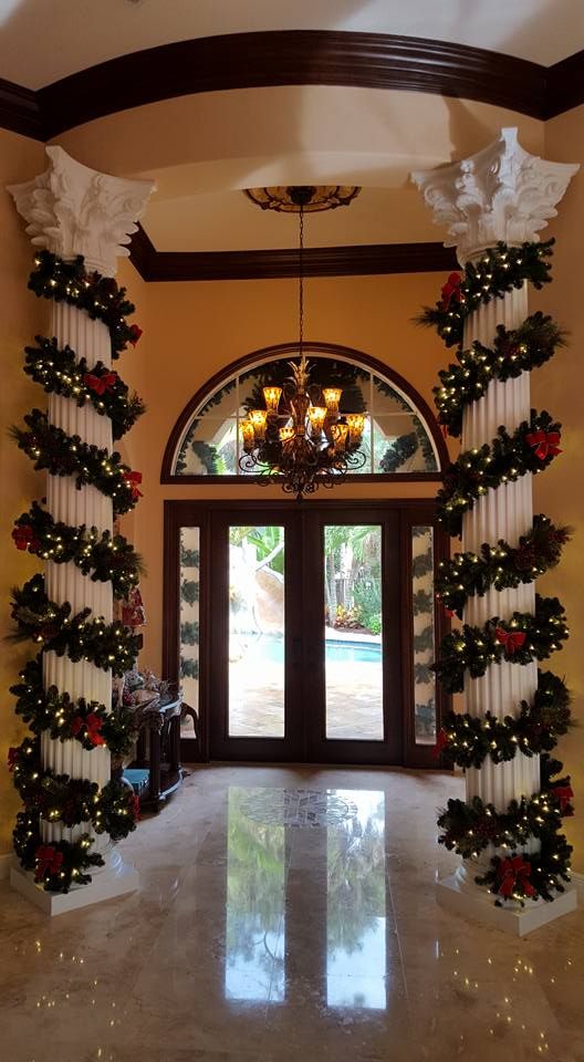 an entry way decorated for christmas with holiday decorations on the columns and wreaths hanging from the ceiling