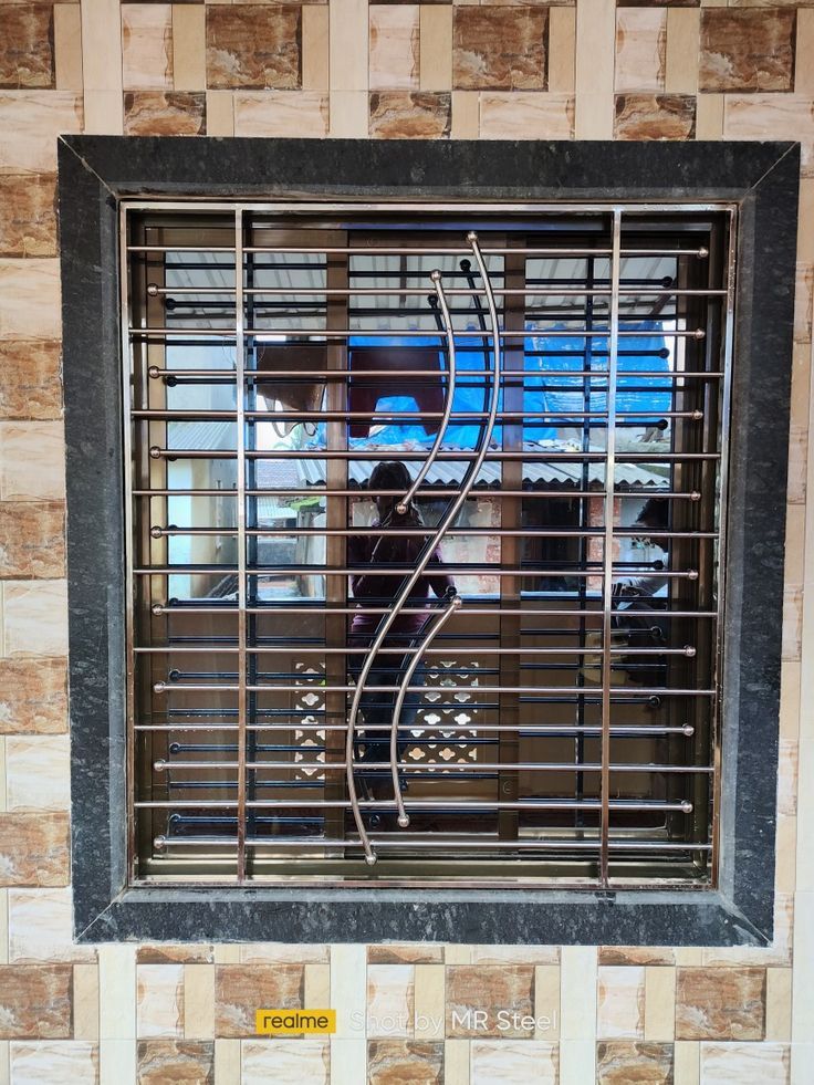 a window with metal bars on it in front of a brick wall and tiled floor