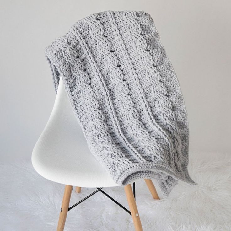 This is a fun project for anyone who loves the look of cables. The resulting blanket is not only beautiful to look at, but also super snuggly and warm. Materials: Size K-10.5 (6.5 mm) Crochet Hook. 14 Skeins Paintbox Yarns Simply Chunky Yarn in Misty Grey. Scissors. Measurements: Finished blanket measures: 33″ Wide X 59″ Long. Skill Level: Intermediate. Crochet Cable Blanket, Beginner Crochet Blanket, Crochet Blanket Border, Cables Blanket, Striped Crochet Blanket, Throw Pillow Pattern, Throw Blanket Pattern, Chunky Crochet Blanket, Cozy Crochet Patterns