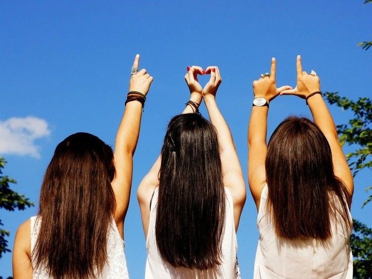 three girls are holding their hands up in the air and making a heart shape with their hands