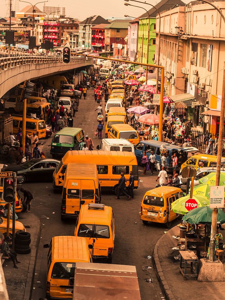 a busy city street filled with lots of traffic and people walking on the side walk