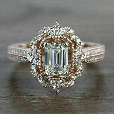 a fancy engagement ring with an emerald center surrounded by white and yellow diamonds on a wooden surface