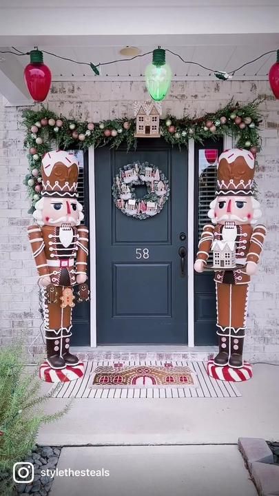 two large gingerbreads are standing in front of a door decorated with garland and lights