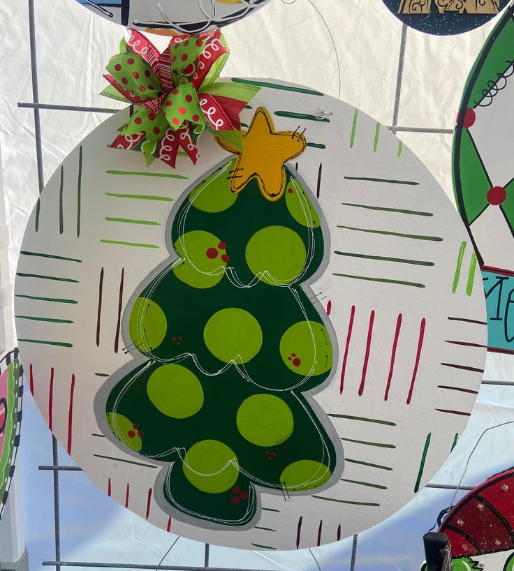 a christmas ornament hanging from the side of a white plate with a green tree on it