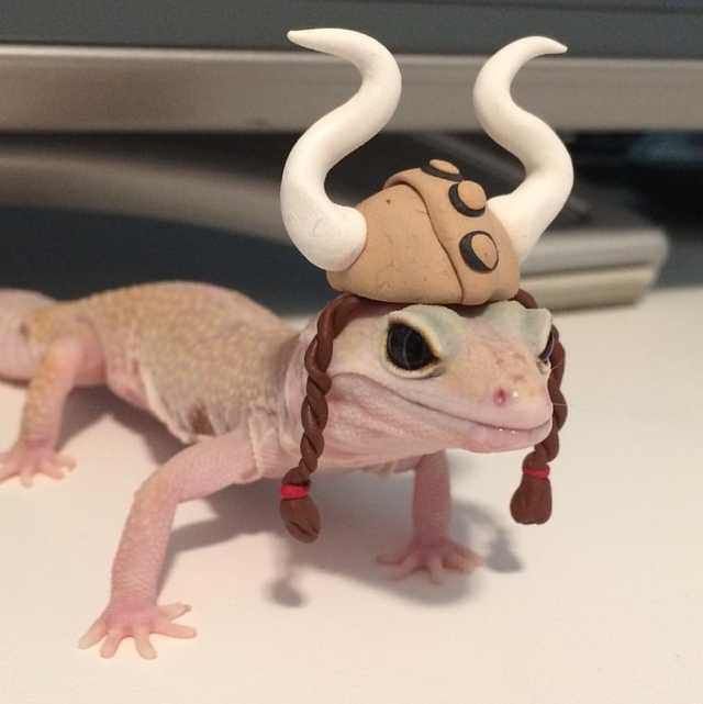 a lizard with horns and a hat on it's head sitting on a desk