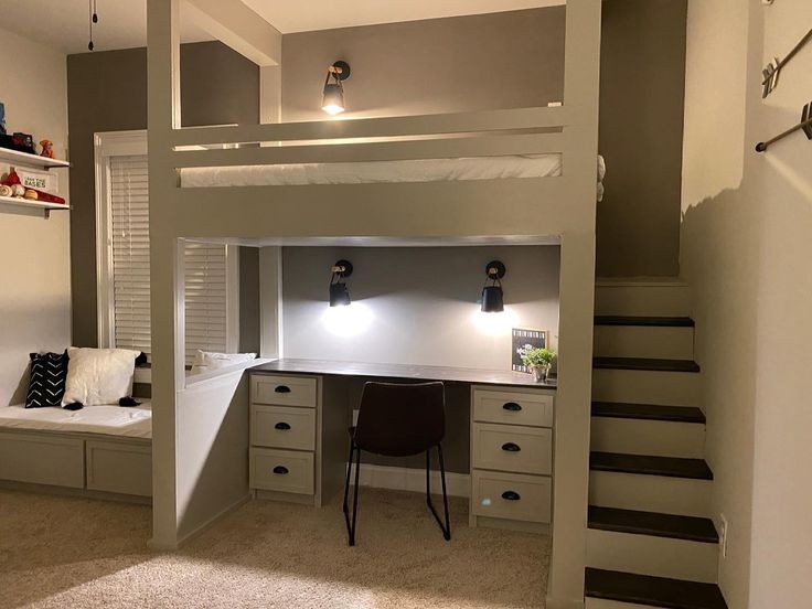 a loft bed with desk underneath and stairs leading up to the upper level, along with built - in storage space