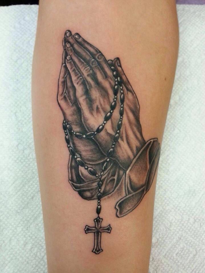 a tattoo on the leg of a woman with a rosary and praying hands