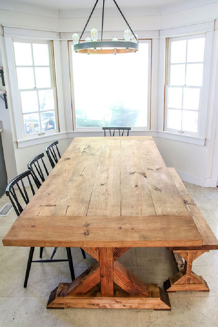 a large wooden table sitting in the middle of a room next to two chairs and a window