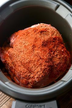 a close up of a meat in a crock pot on a wooden table top