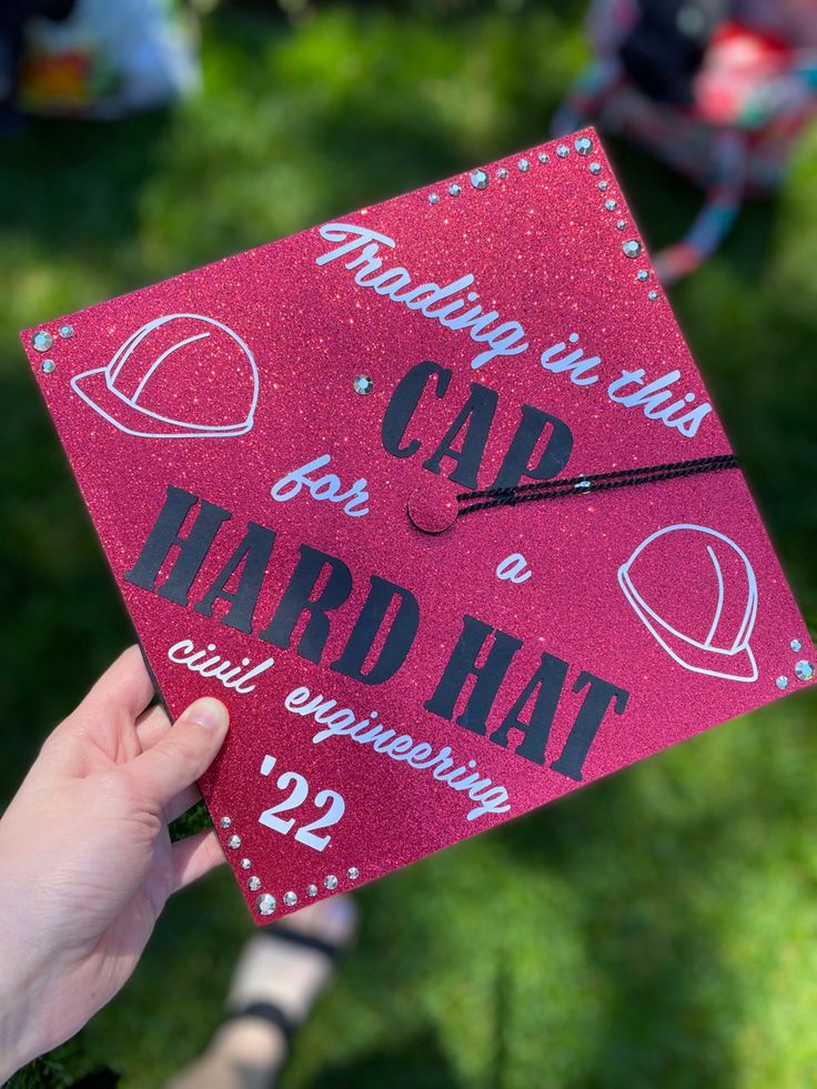 someone holding up a pink graduation cap with the words cap hard written on it in front of them