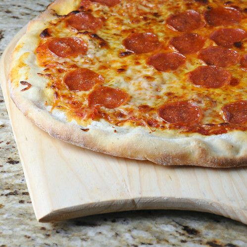 a pepperoni pizza sitting on top of a wooden cutting board