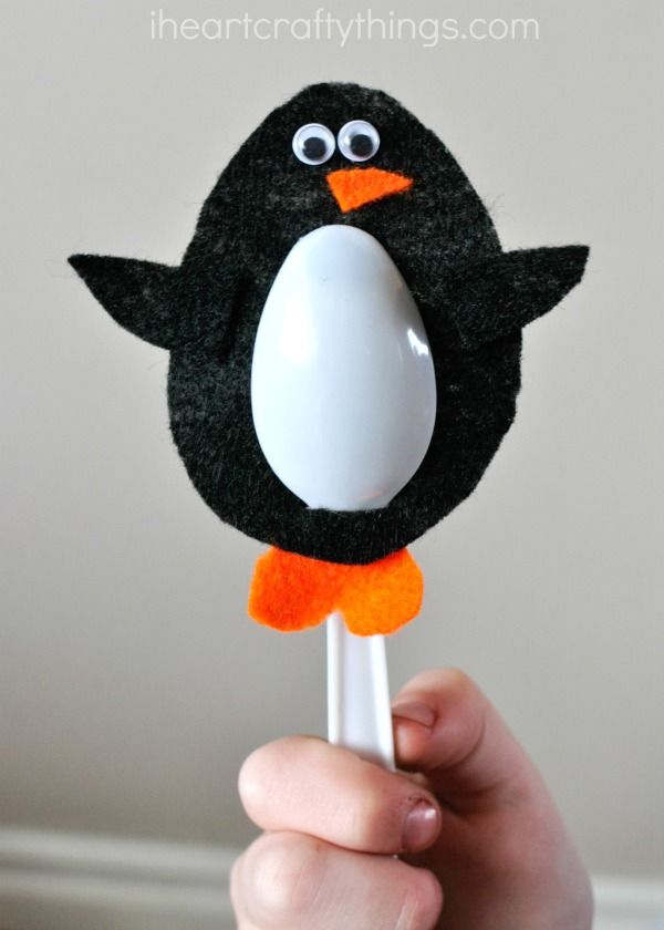 a hand holding a lollipop with a black and white penguin on it's head