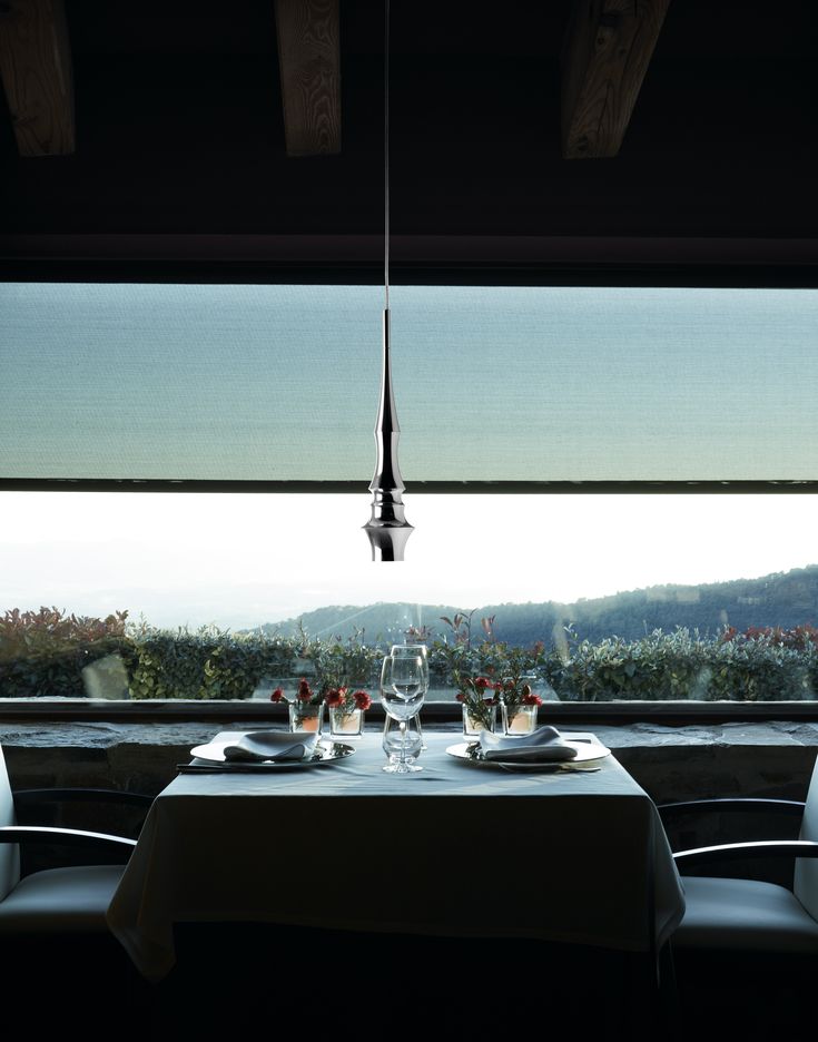 the table is set for two with wine glasses and plates on it in front of an open window