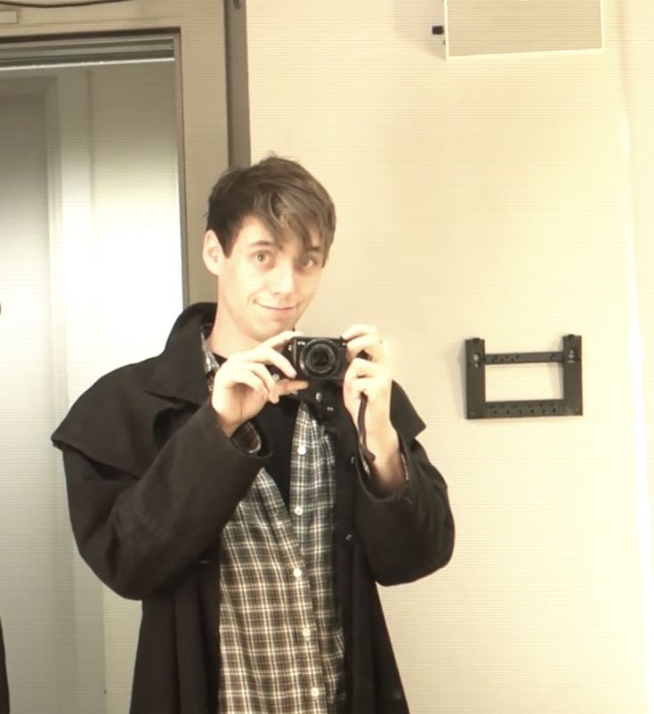 a man taking a selfie in front of a mirror with his camera and jacket on