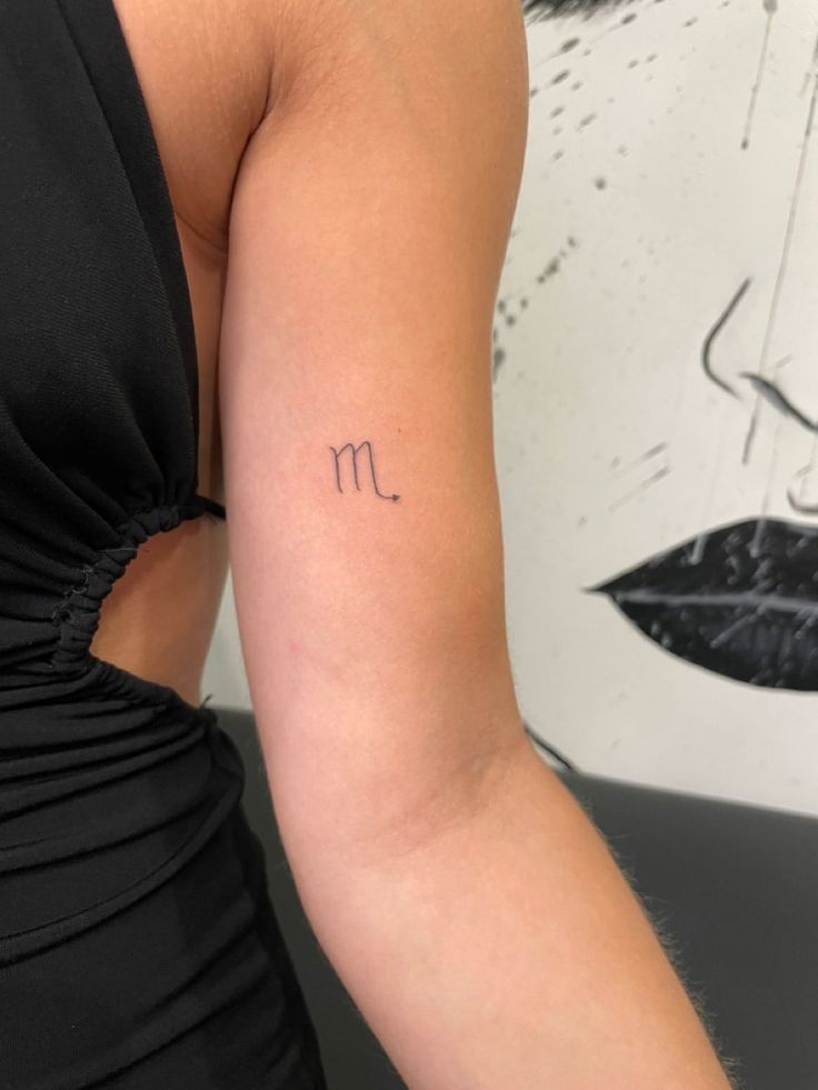 a woman's arm with a small tattoo on the upper half of her arm