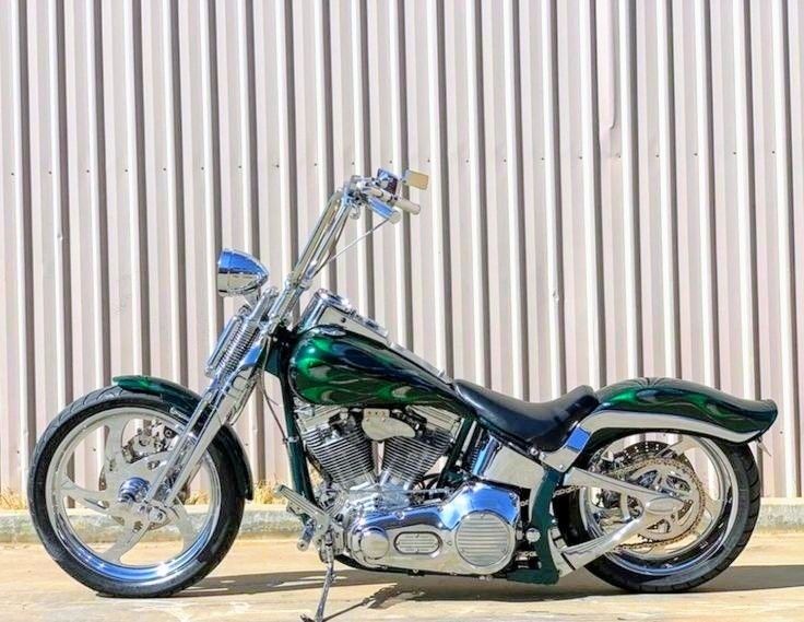 a green motorcycle parked in front of a metal building with no doors on the side