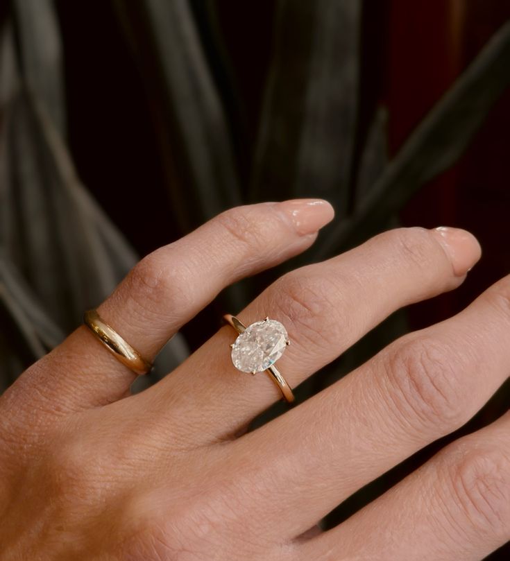 a woman's hand with two gold rings and a diamond ring on her finger