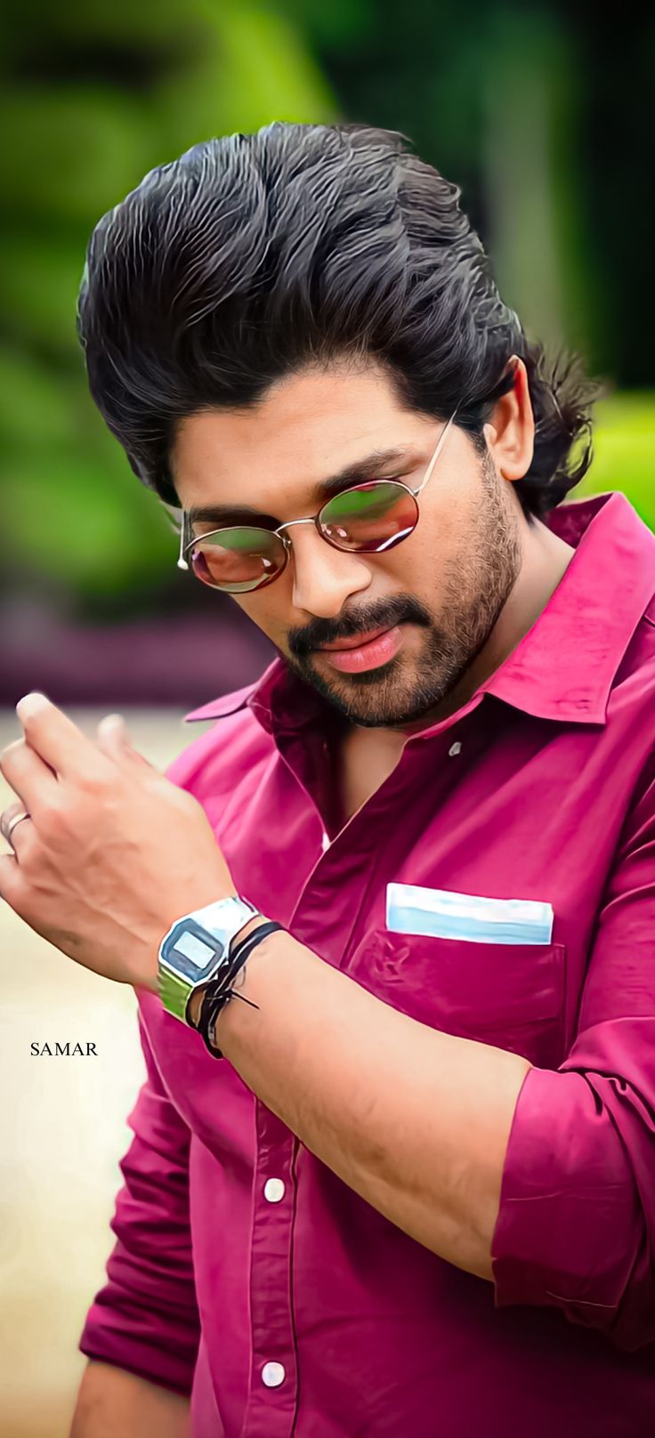 a man in a pink shirt is looking at his cell phone while wearing sunglasses and a watch