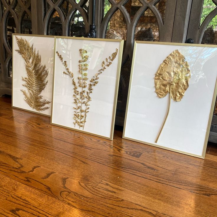 three framed art pieces sitting on top of a wooden table