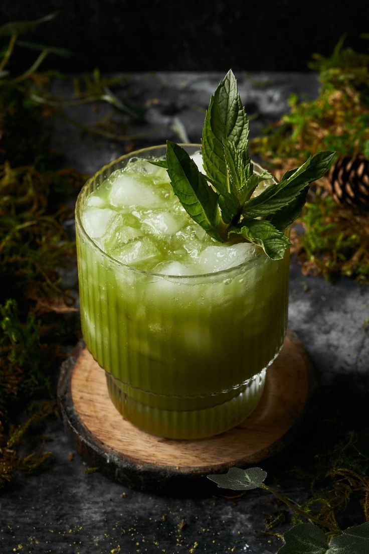 a green drink sitting on top of a wooden coaster