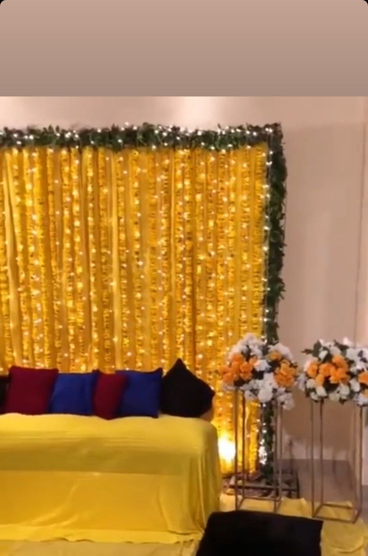 a room with yellow drapes and flowers on the bed