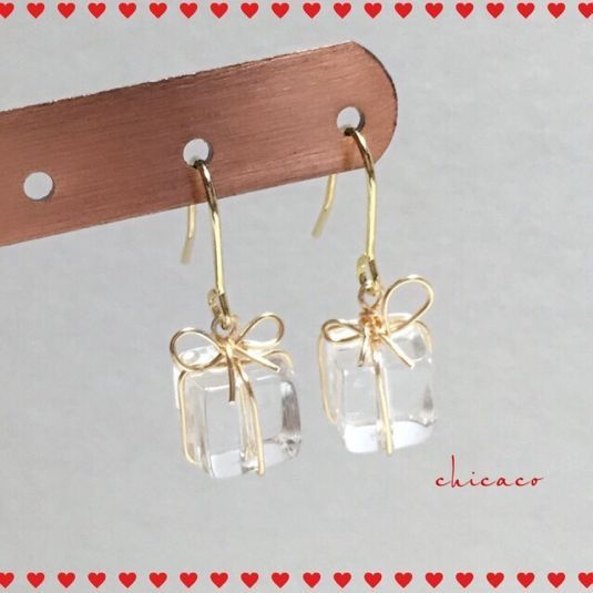 the earrings are adorned with clear glass cubes and a gold bow on each side