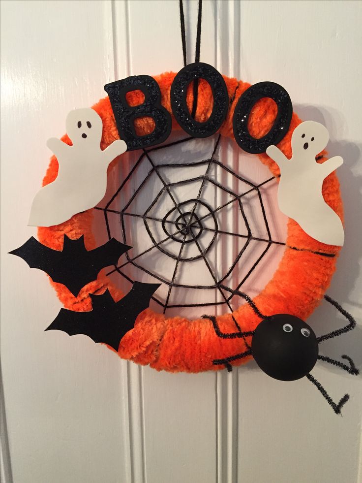 a halloween wreath decorated with black and orange decorations, ghostes and boo - eyes