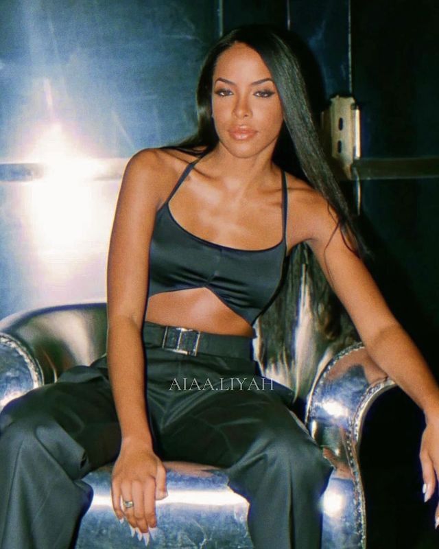 a woman sitting on top of a silver chair in a black bra and matching pants