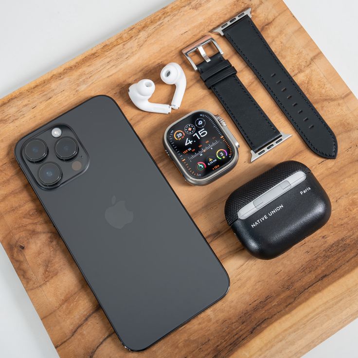 an apple watch, headphones, and other accessories are on a wooden table top