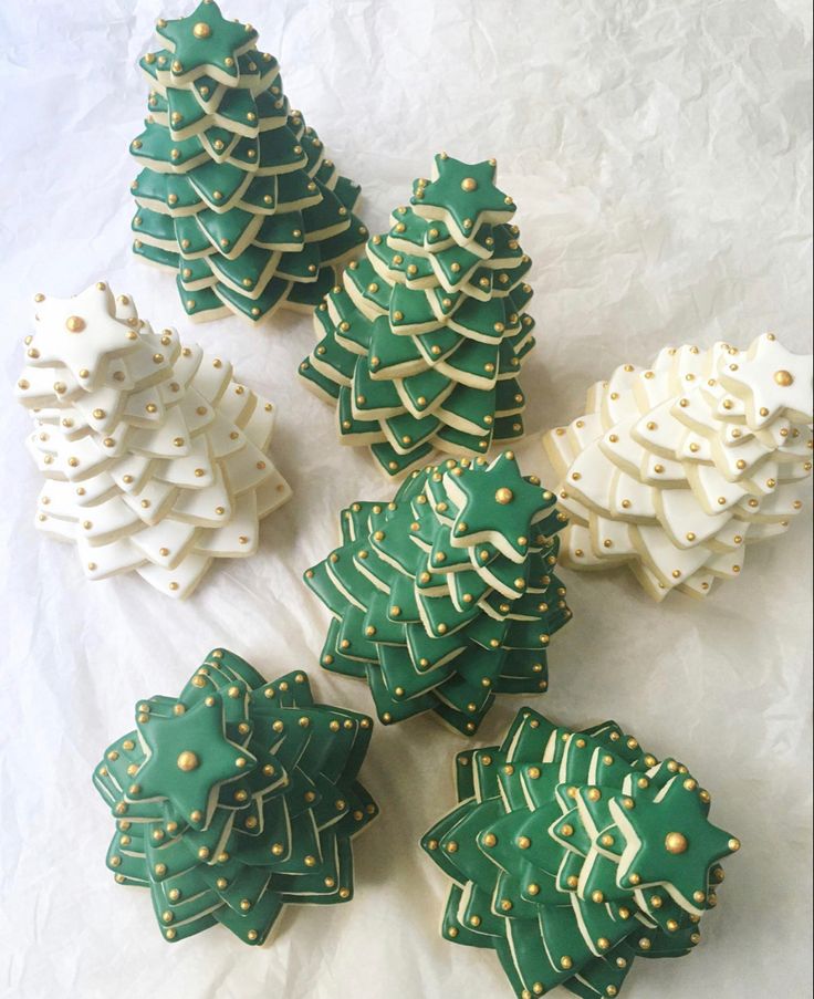 decorated cookies are arranged in the shape of christmas trees on a white tablecloth background