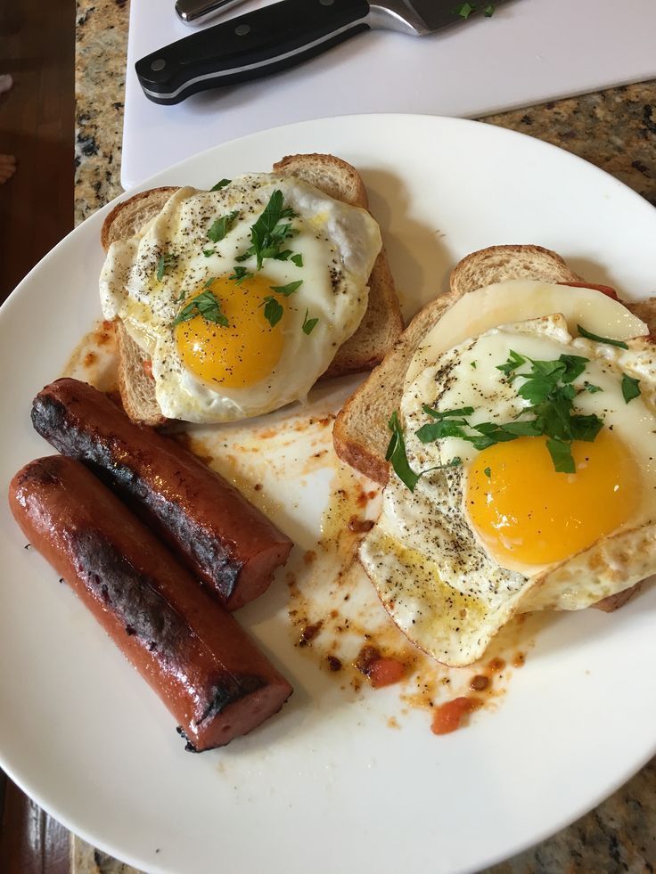 two eggs and sausages are on a white plate