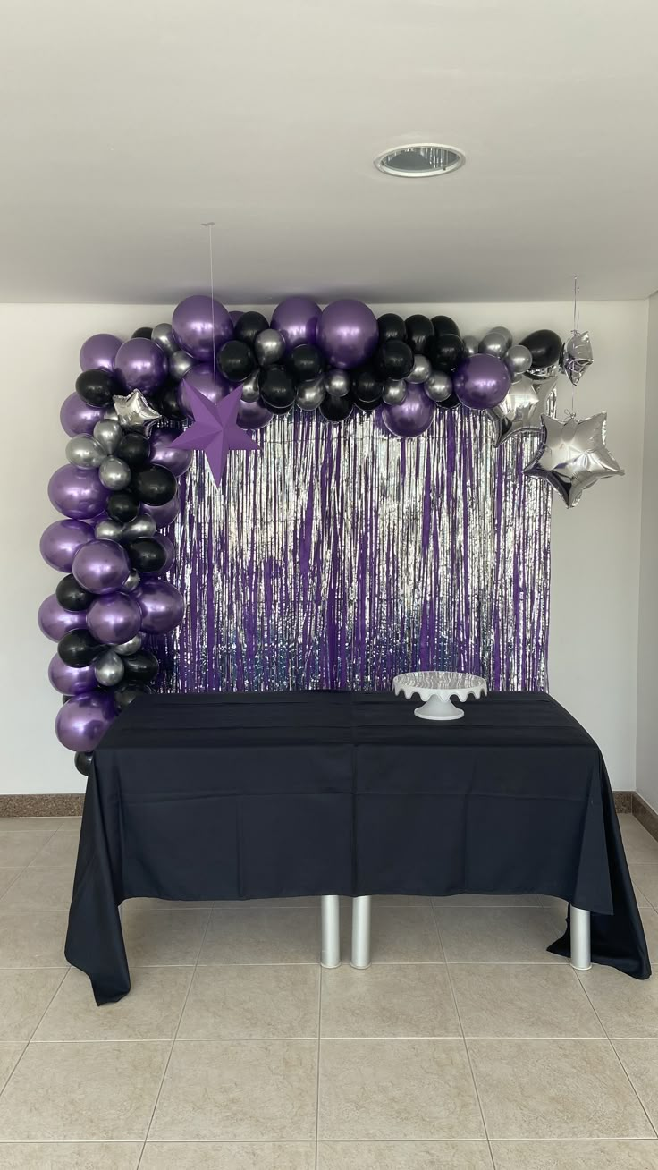 a black table topped with purple and black balloons