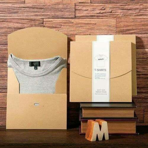 an open cardboard box with a t - shirt in it and some books on the table