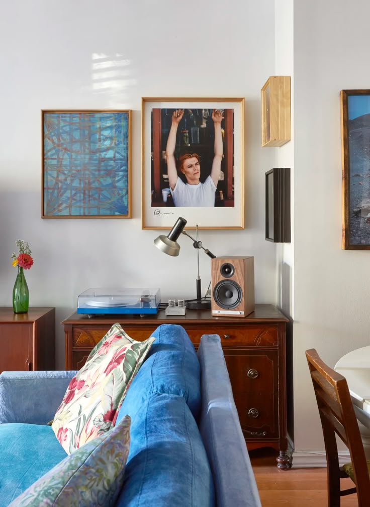 a living room with blue couches and pictures hanging on the wall above it's head