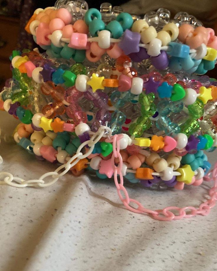 a bunch of bracelets that are on top of a white table with some beads