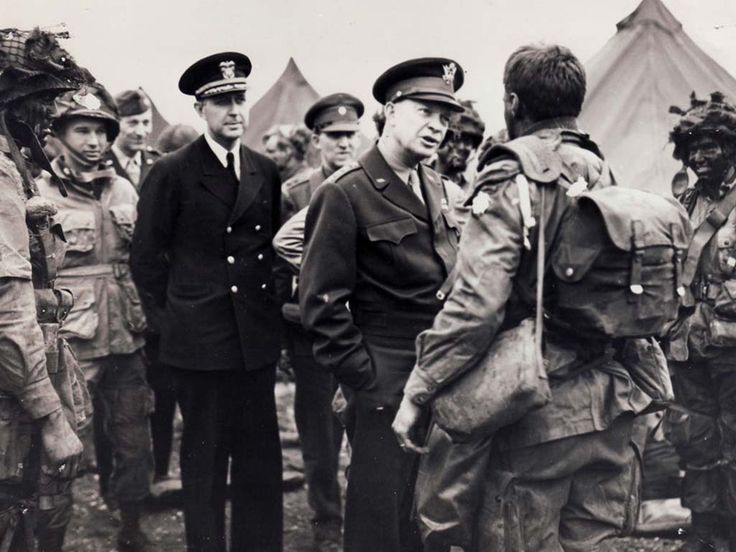 a group of men standing next to each other in front of a forest filled with trees