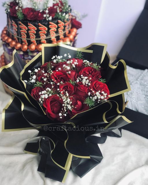 a bouquet of red roses sitting on top of a white bed next to a cake