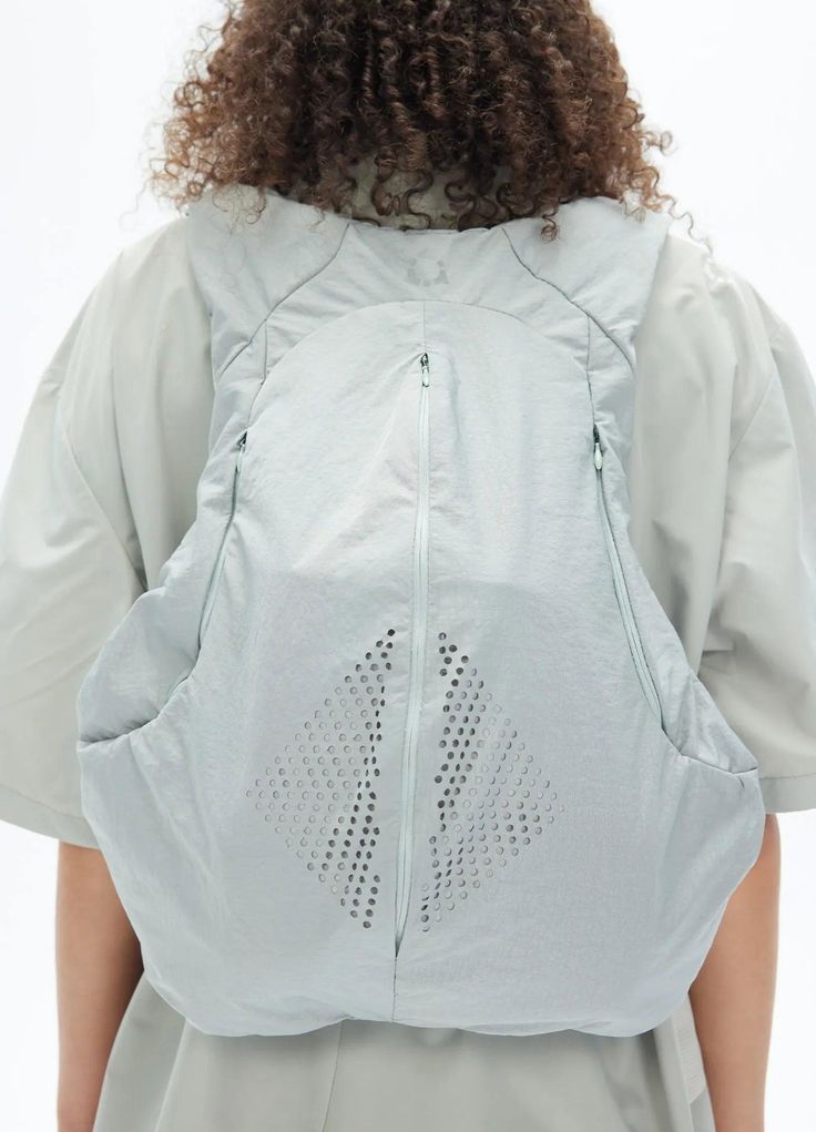 the back of a woman wearing a white jacket with an open zipper on her chest