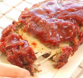 someone is holding a piece of meatloaf on a white plate with gravy