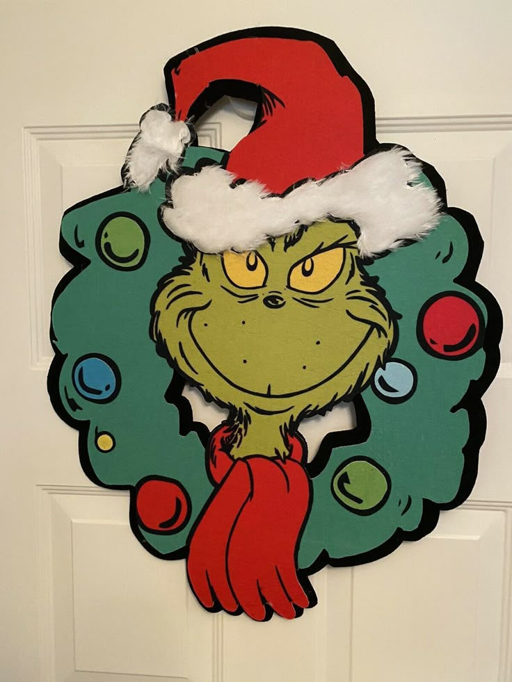 the grinch door hanger is decorated with santa's hat