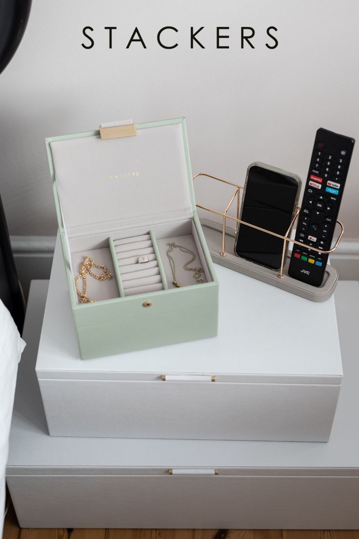 an open box with jewelry and a remote control sitting on top of a white table