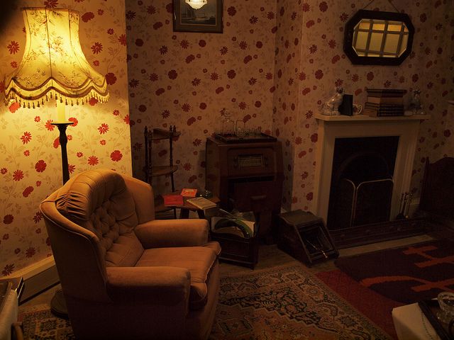 a living room filled with furniture and a lamp on top of a wooden table next to a fire place